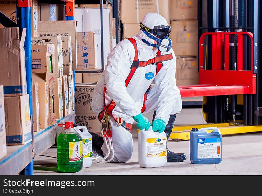 Worker in hazardous materials suit and ventilator handling industrial chemicals inside warehouse. Worker in hazardous materials suit and ventilator handling industrial chemicals inside warehouse.