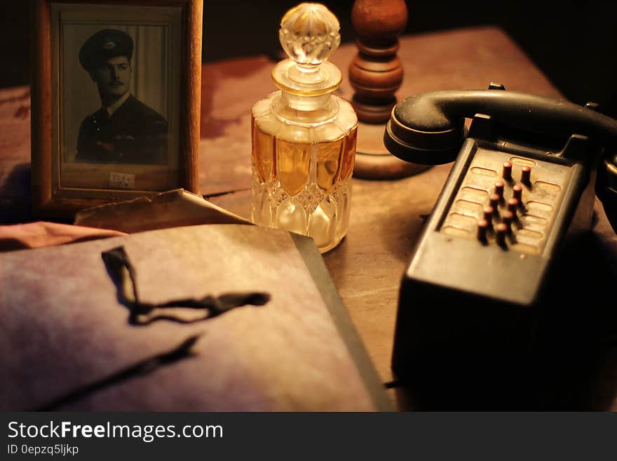 Black and Gray Vintage Telephone Near Glass Perfume Bottle