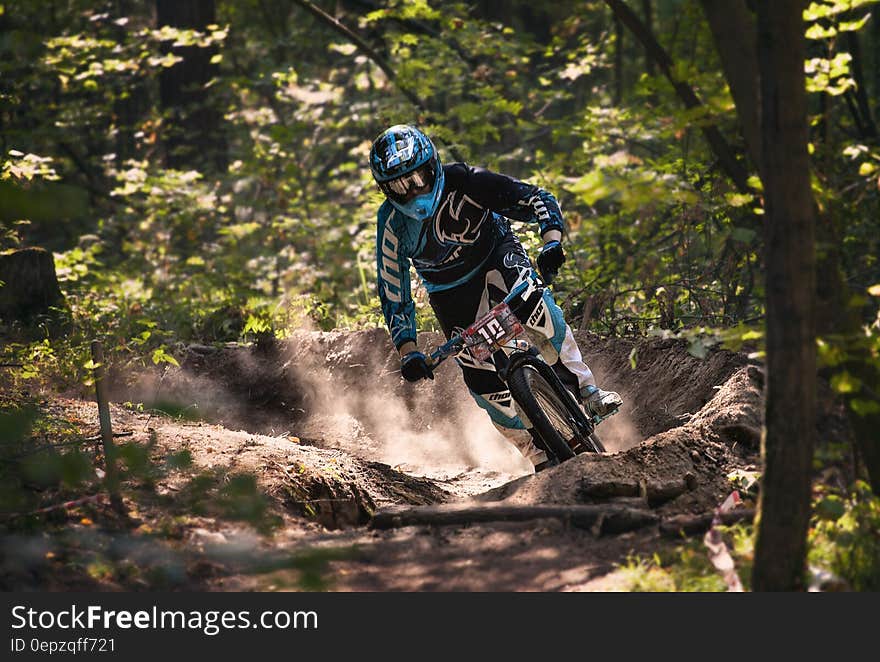 A motocross biker driving through forest.