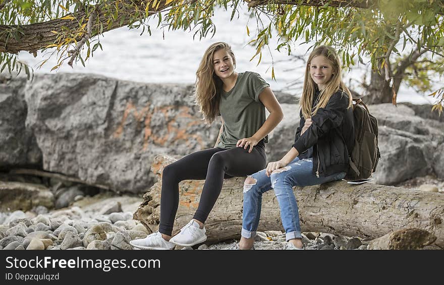 2 Women Sitting on Rock during Daytime