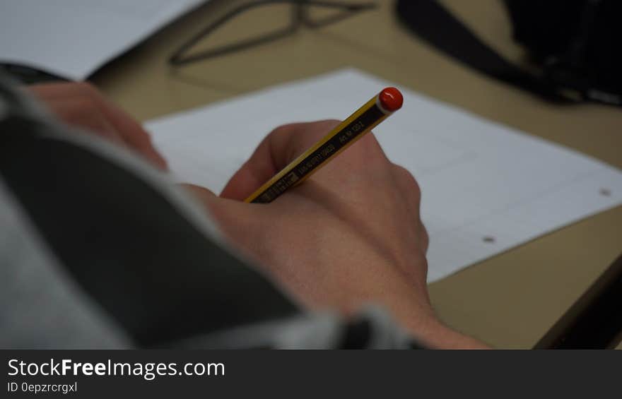 Hand of child writing with wooden pencil on desktop. Hand of child writing with wooden pencil on desktop.