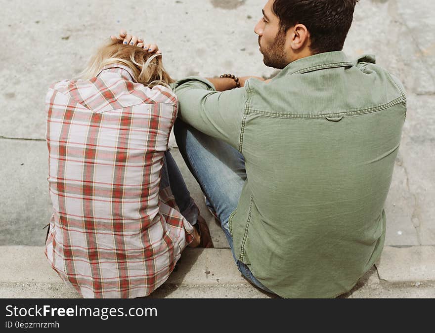 Man and Woman Sitting on Sidewalk