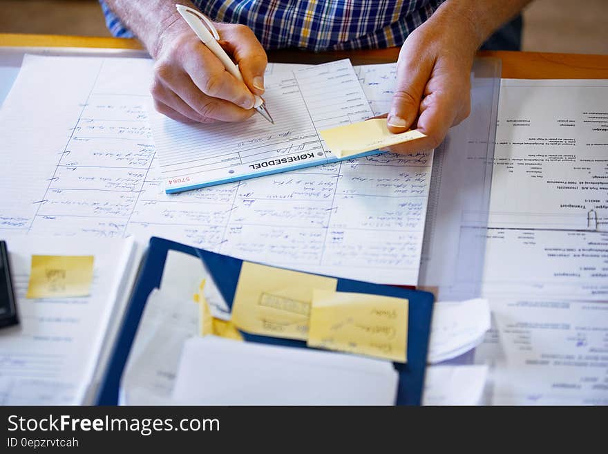 Man using pen to fill form seated at desk. Man using pen to fill form seated at desk.