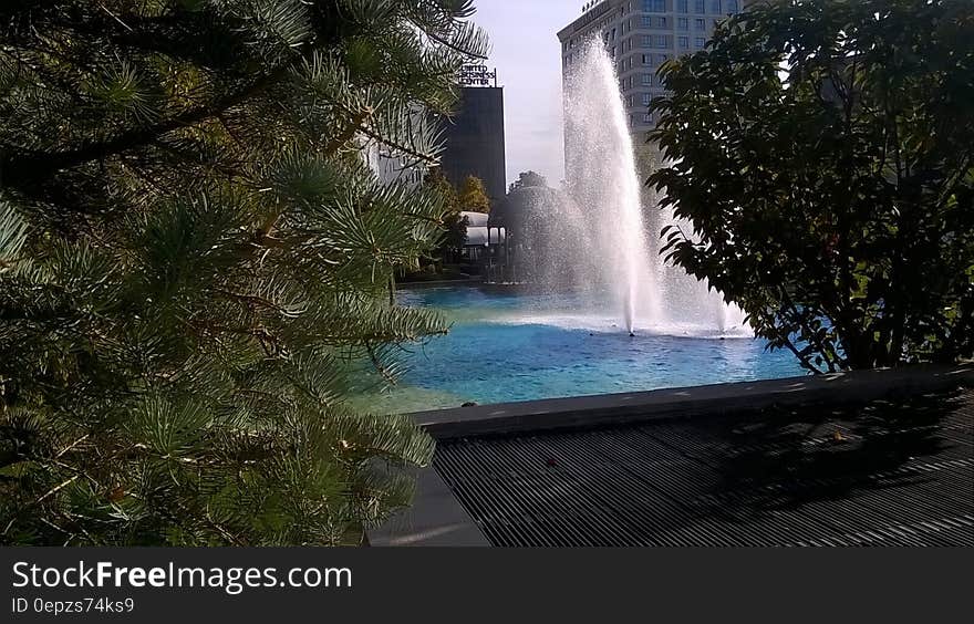 Fountain surrounded by modern architecture in city on sunny day. Fountain surrounded by modern architecture in city on sunny day.