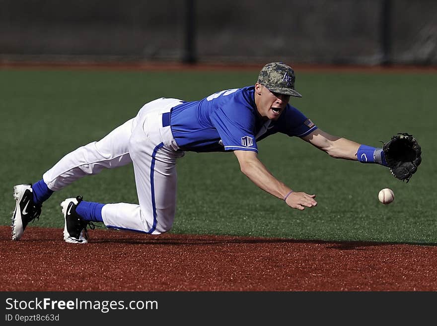 Baseball Player Wearing Blue and White Jersey Catching Baseball