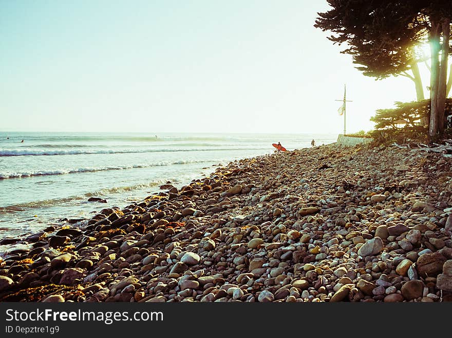 Surfer carrying board on rocky coastline. Surfer carrying board on rocky coastline.