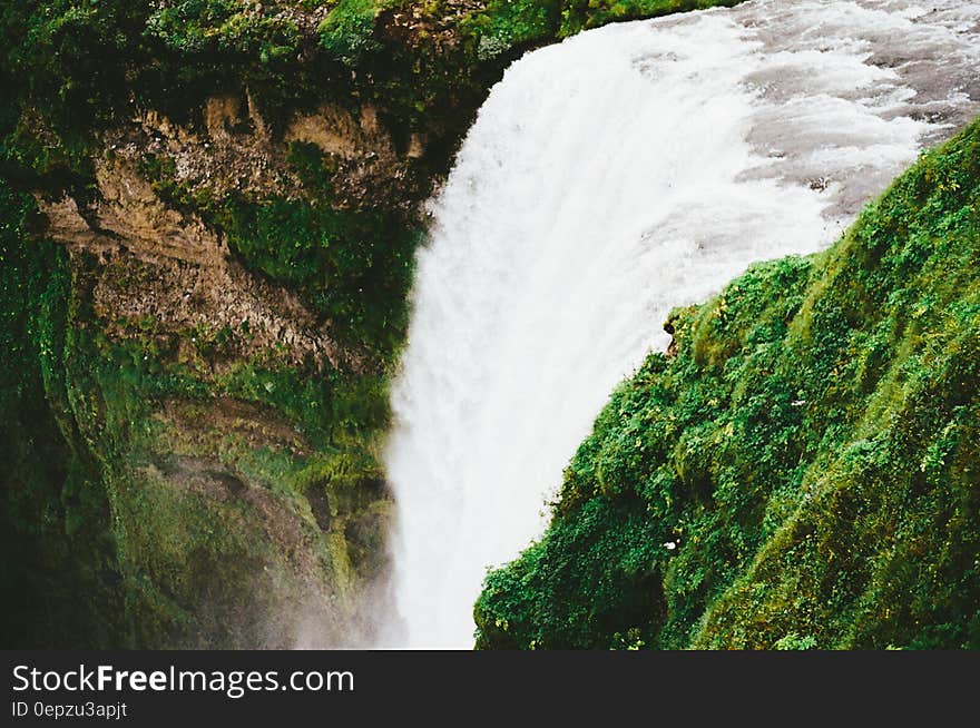 Waterfalls over cliff along green shores on sunny day. Waterfalls over cliff along green shores on sunny day.