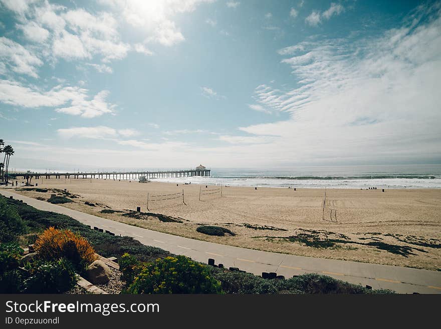 An aerial view of a long sandy beach and a wooden pontoon in the background. An aerial view of a long sandy beach and a wooden pontoon in the background.