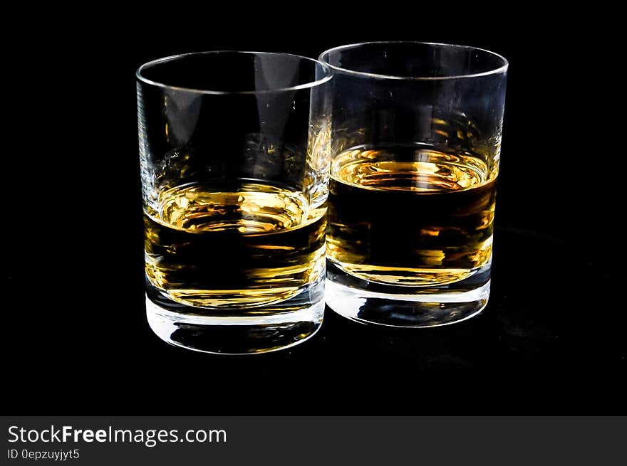 Glasses of whiskey on black background.