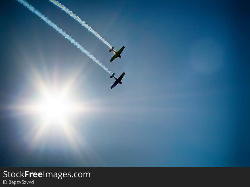 Two Airplane Flying Under Blue Sky Emitting White Smoke