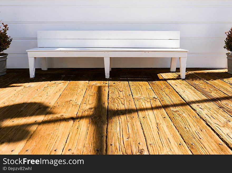 Empty white painted wooden bench on wooden plank deck on sunny day. Empty white painted wooden bench on wooden plank deck on sunny day.