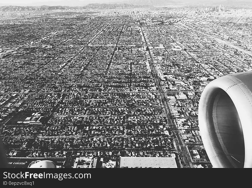 Black and white white of aircraft engine flying over sprawling cityscape. Black and white white of aircraft engine flying over sprawling cityscape.