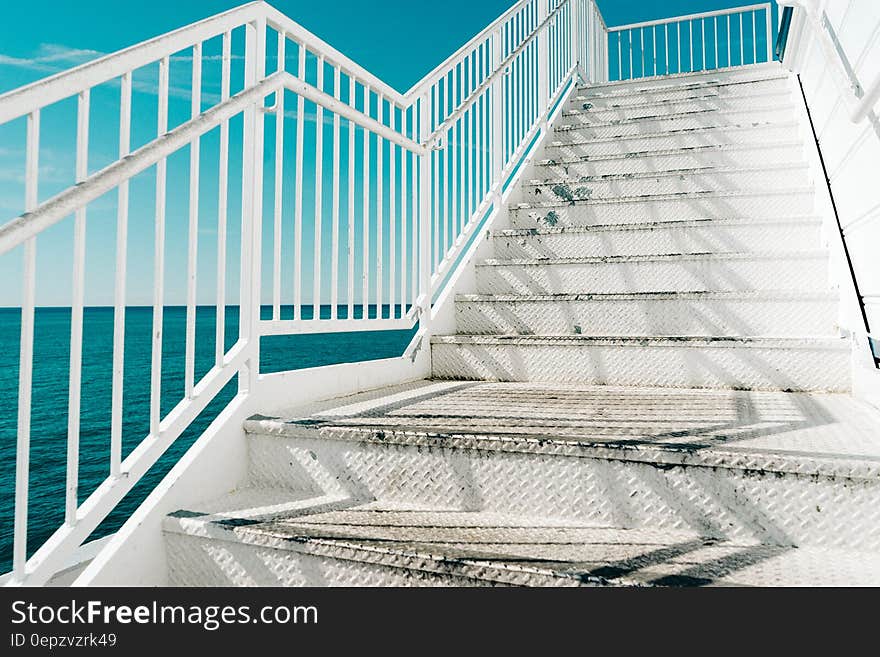 White outdoors staircase by the sea with blue sky background.