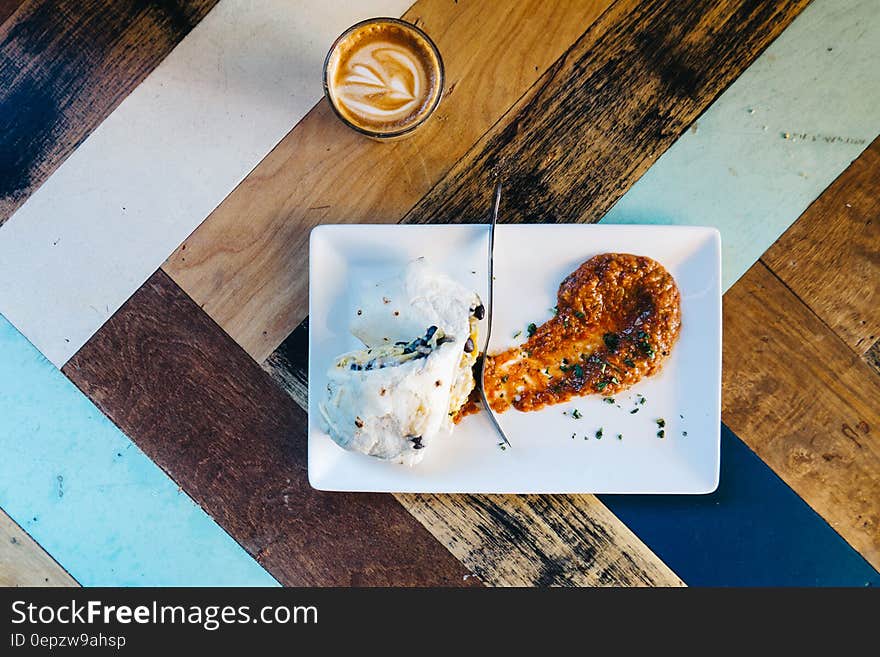 Overhead view of Mexican burrito and cup of coffee on wooden table with striped effect. Overhead view of Mexican burrito and cup of coffee on wooden table with striped effect.