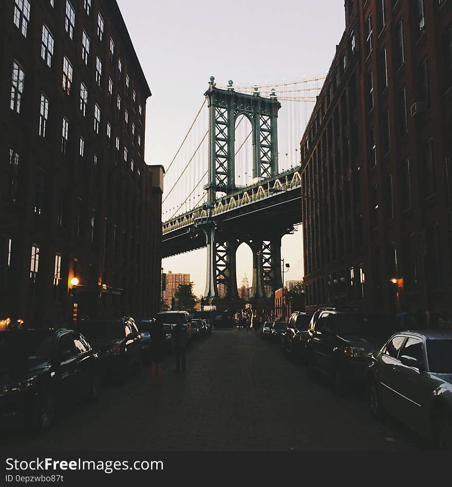 Brooklyn Bridge in New York city with cars parked on street in foreground, USA.