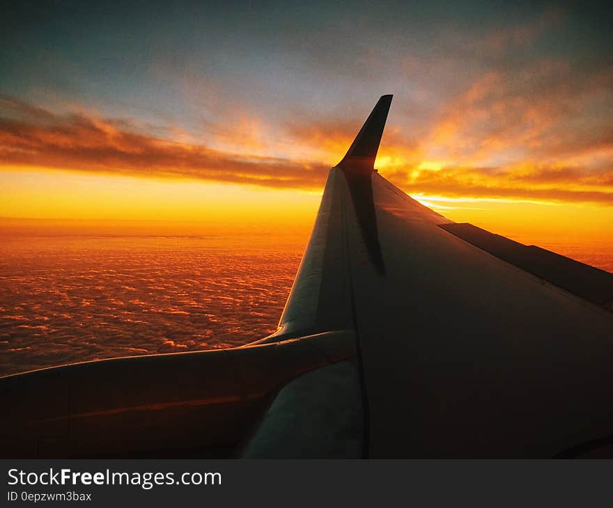 An airplane wing above open sea at sunset. An airplane wing above open sea at sunset.