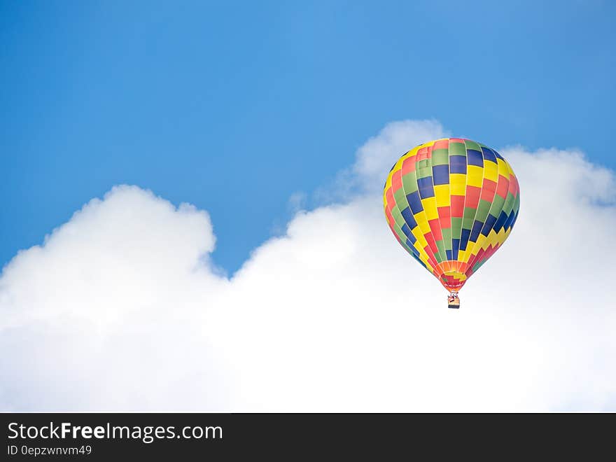 Yellow Blue and Green Hot Air Balloon Flying Near White Clouds