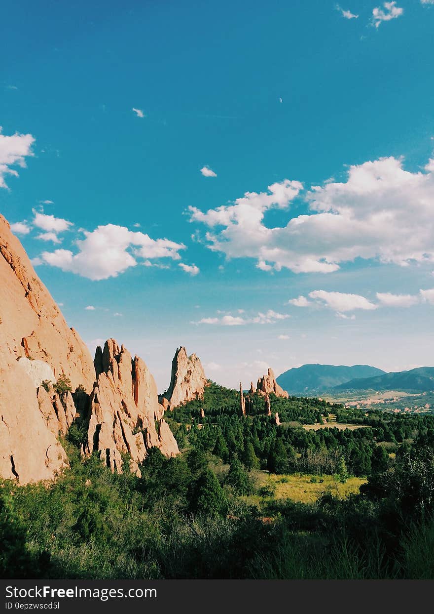 A landscape with steep mountains and green forests with blue skies. A landscape with steep mountains and green forests with blue skies.