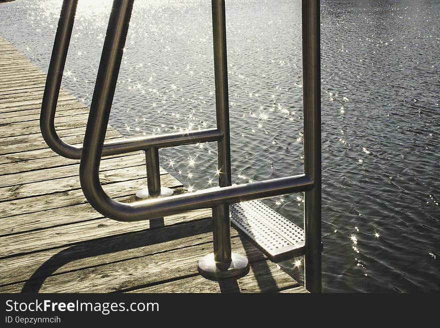 Metal ladder on wooden dock by glistening sea. Metal ladder on wooden dock by glistening sea.