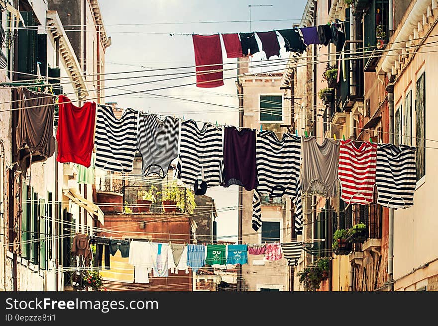 Striped Shirt Hanging on Gray Wire Between Beige Painted Wall Building during Daytime