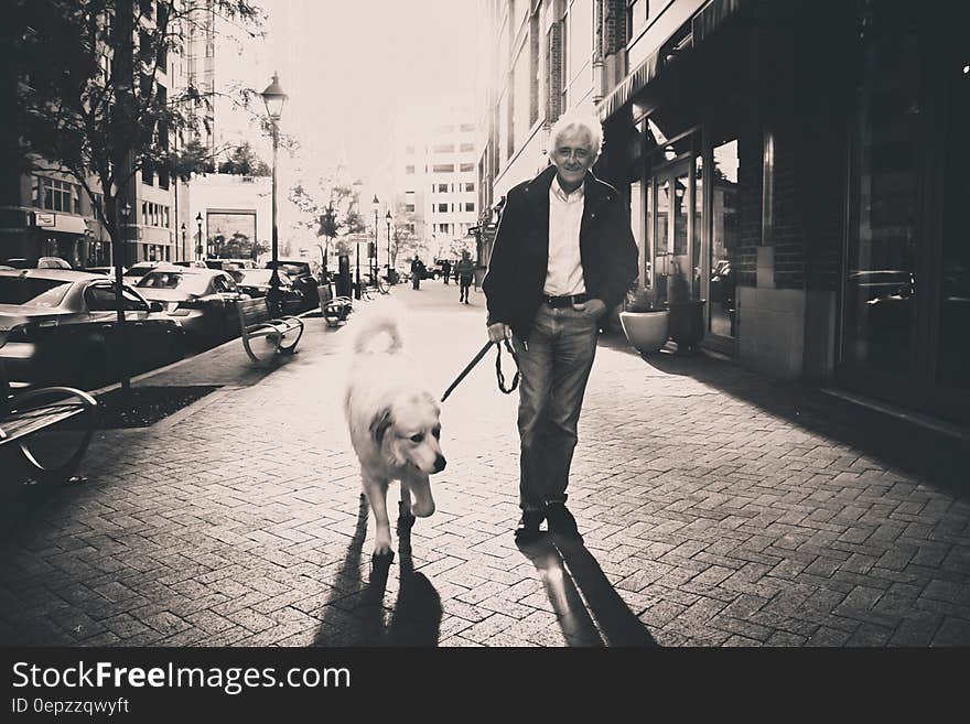 Portrait of man walking dog on city streets in black and white.