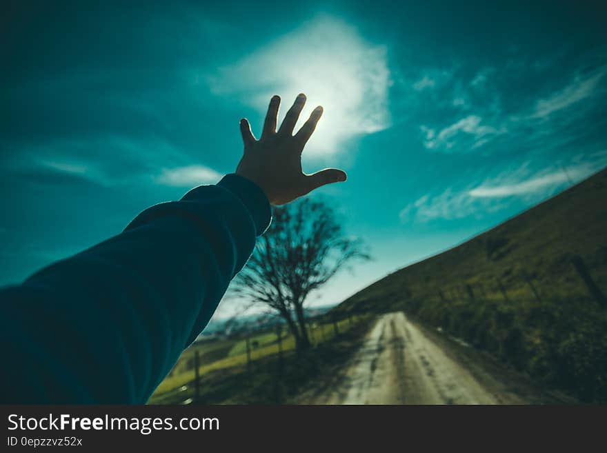 Person Raising Hand Towards Blue Sky during Daytime