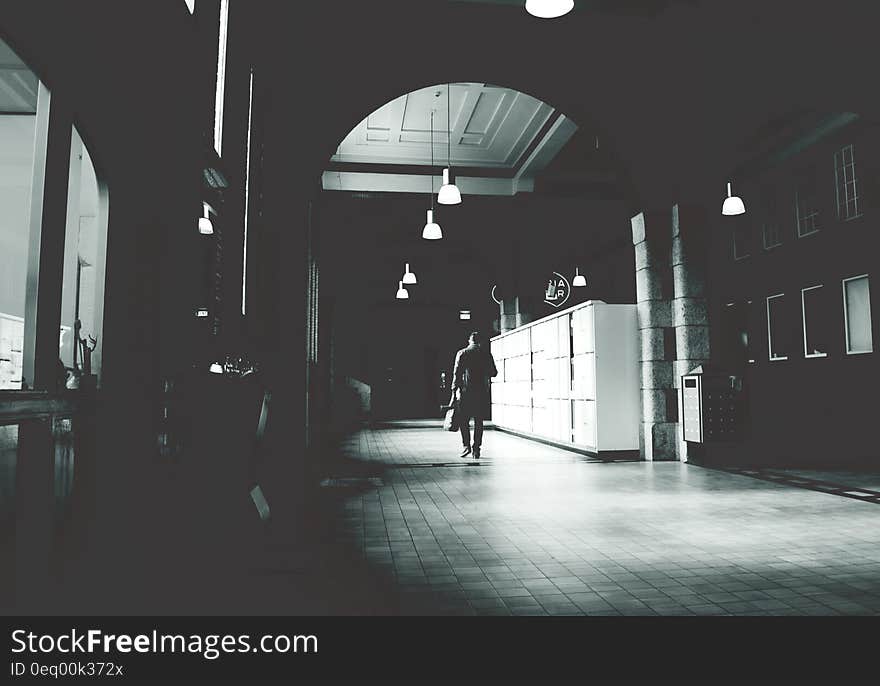 Silhouette of a Person Walking on a Grey Floor Tiles Beside White Cabinet in Dark Room