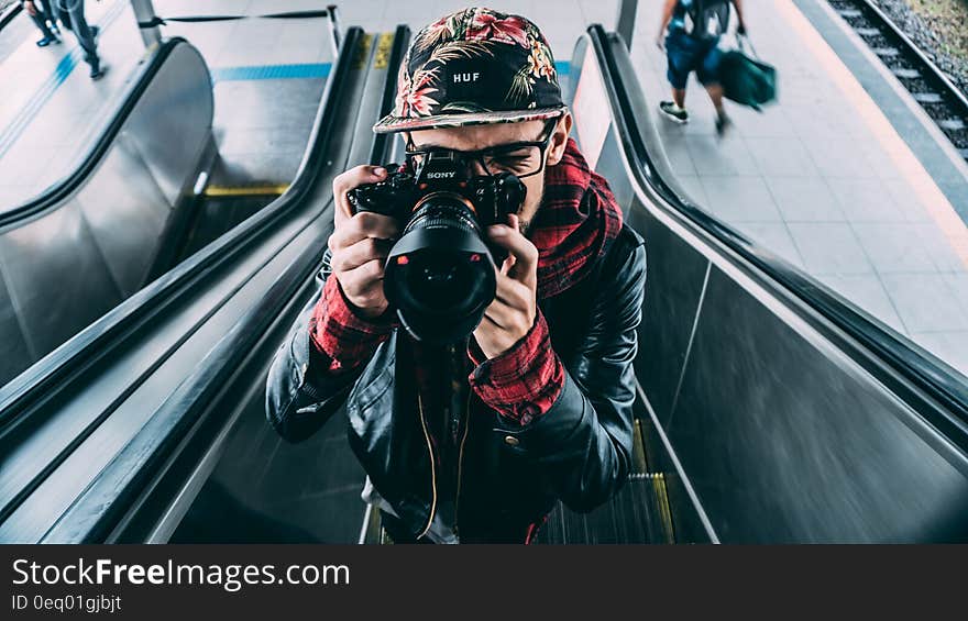 Man Wearing Black Leather Zip Up Jacket and Dslr Camera