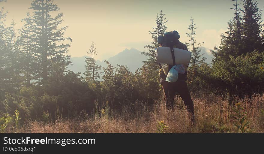 Backpacker hiking across country field on foggy day. Backpacker hiking across country field on foggy day.