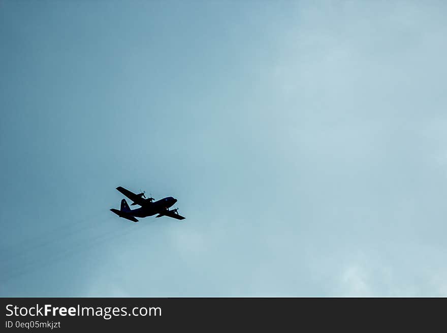 Airplane Against Blue Cloudy Sky Overhead