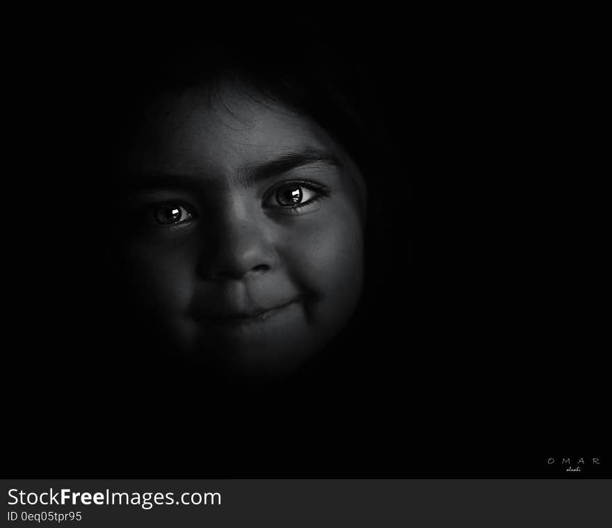 Studio portrait of face of young girl in shadows in black and white. Studio portrait of face of young girl in shadows in black and white.