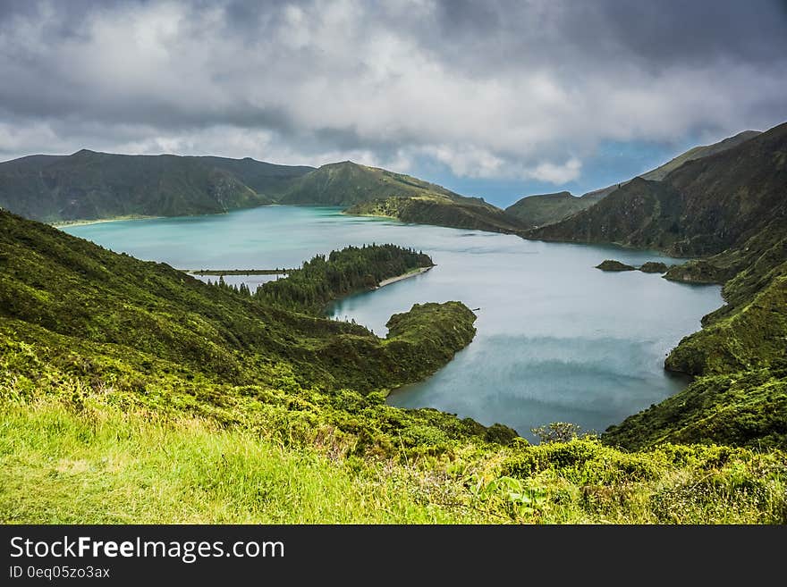 Blue Lake Behind Green Mountain Under White Clouds