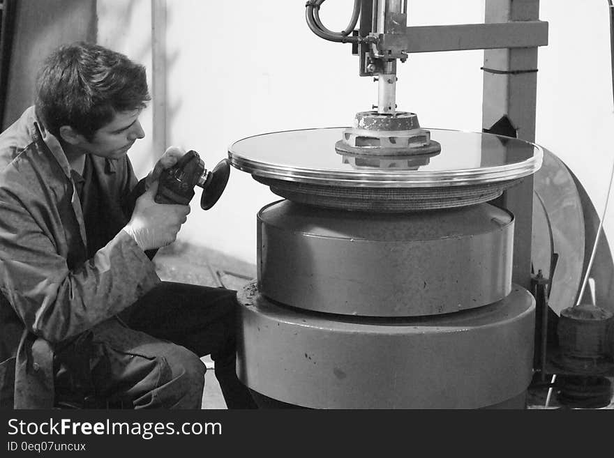 A black and white photo of a craftsman polishing a round metal glass frame. A black and white photo of a craftsman polishing a round metal glass frame.