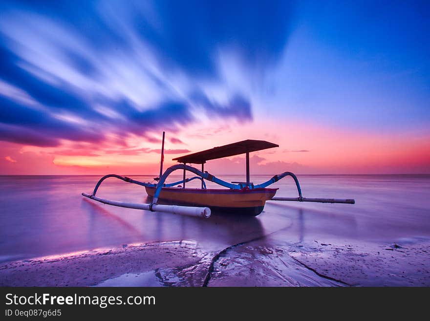 Brown Blue and White Wooden Boat during Orange Sunset