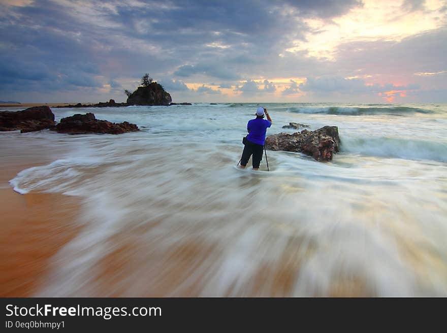 A casually dressed man standing in shallow water on a sandy beach. A casually dressed man standing in shallow water on a sandy beach.