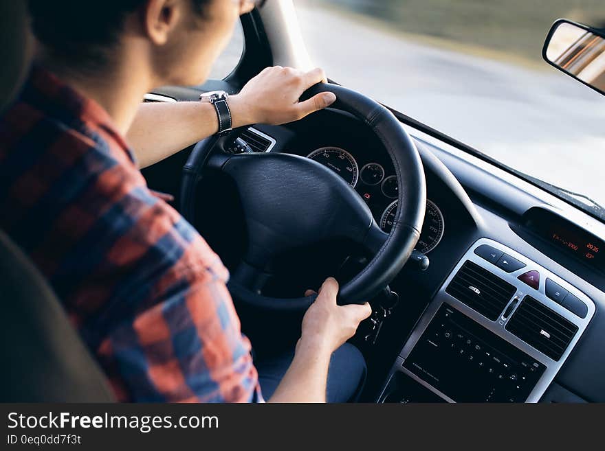 Interior elevated view of young man driving motor car. Interior elevated view of young man driving motor car.