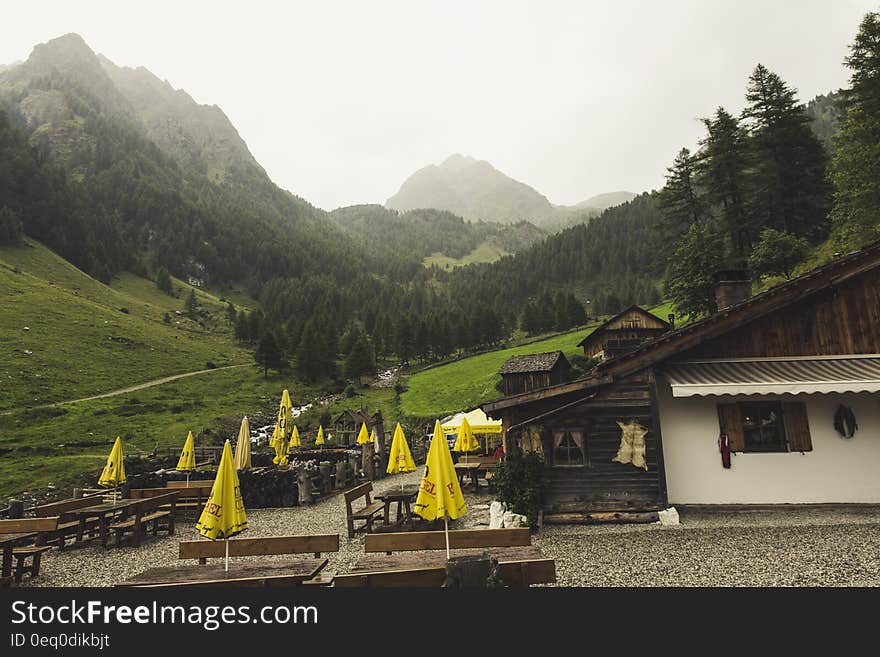 Cafe building with outdoor table and parasols in valley with mountains in background. Cafe building with outdoor table and parasols in valley with mountains in background.