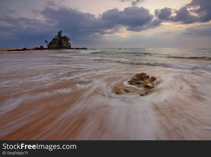 Wide sandy beach at low tide with long exposure view of receding waves.