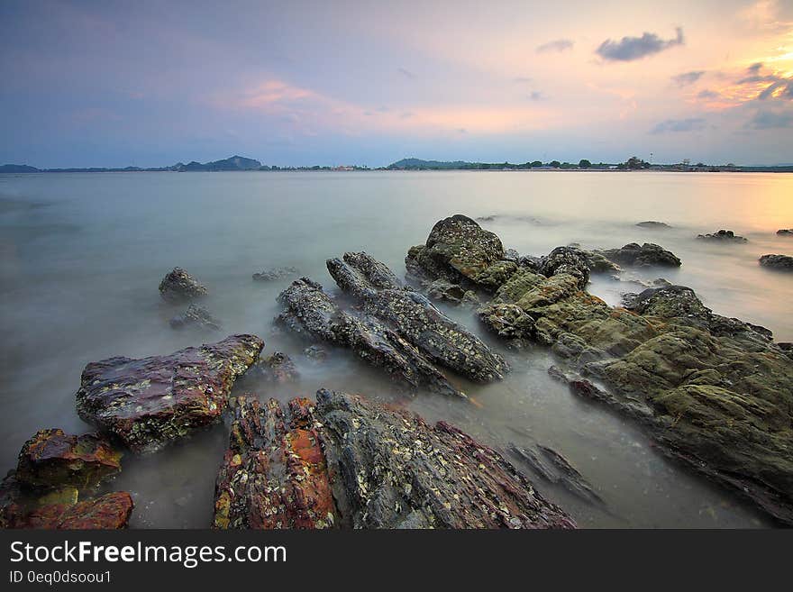 Scenic view of rocky ocean shoreline at sunrise.