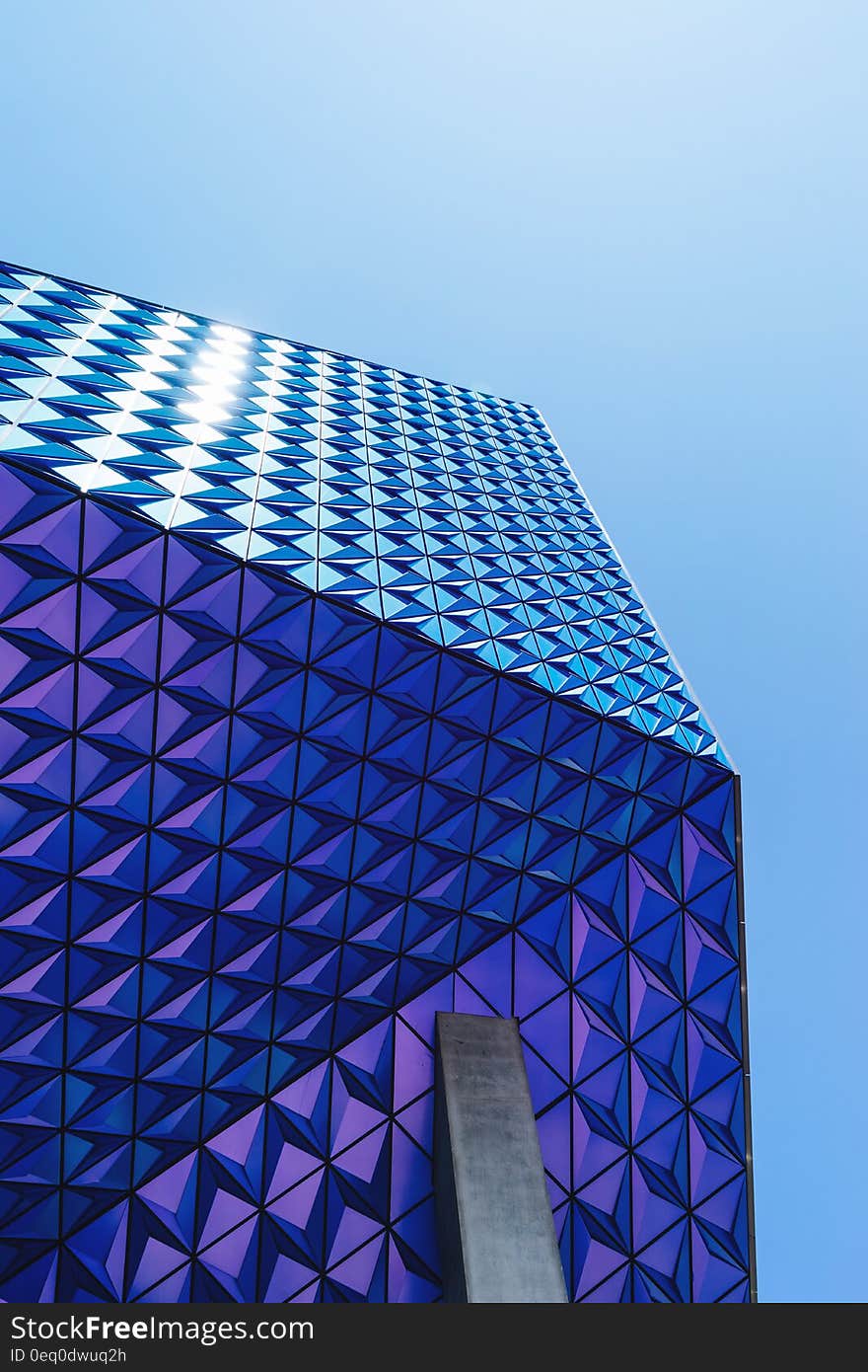 Exterior of geometric patterned blue building with sky background.