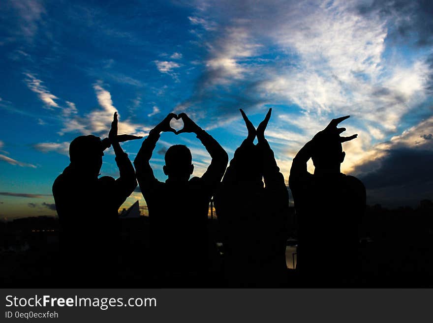 A group of people forming the word "LOVE" with their hands at sunset. A group of people forming the word "LOVE" with their hands at sunset.