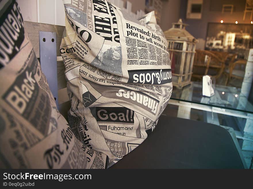 A pair of pillows with newspaper print in a shop or cafe. A pair of pillows with newspaper print in a shop or cafe.