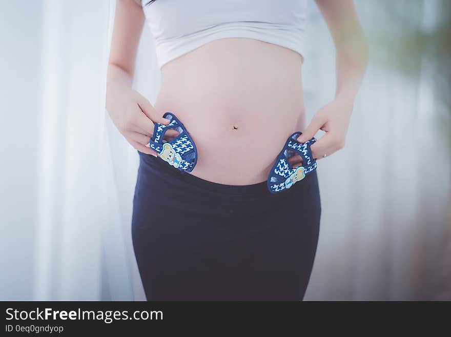 Pregnant Woman Holding Baby Shoes in Her Tummy