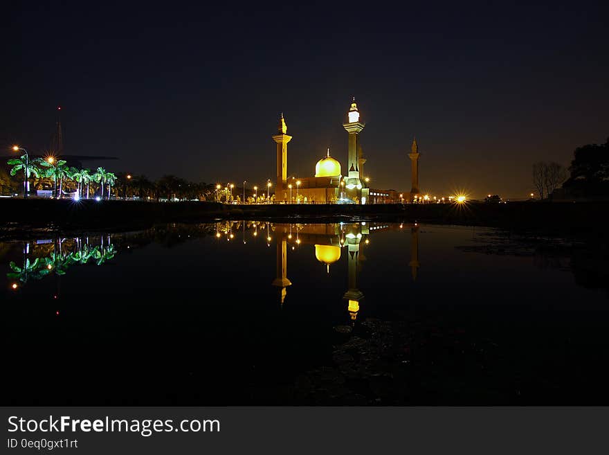 Reflection of Yellow High Rise Tower during Night Time