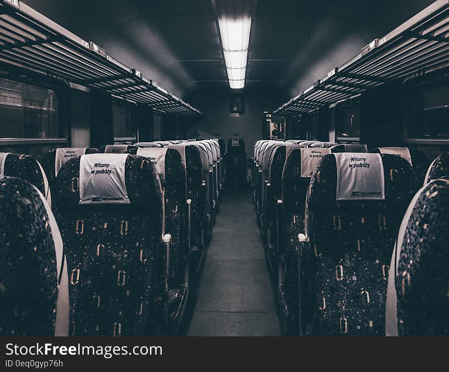 A train wagon interior with empty seats and poor lighting.