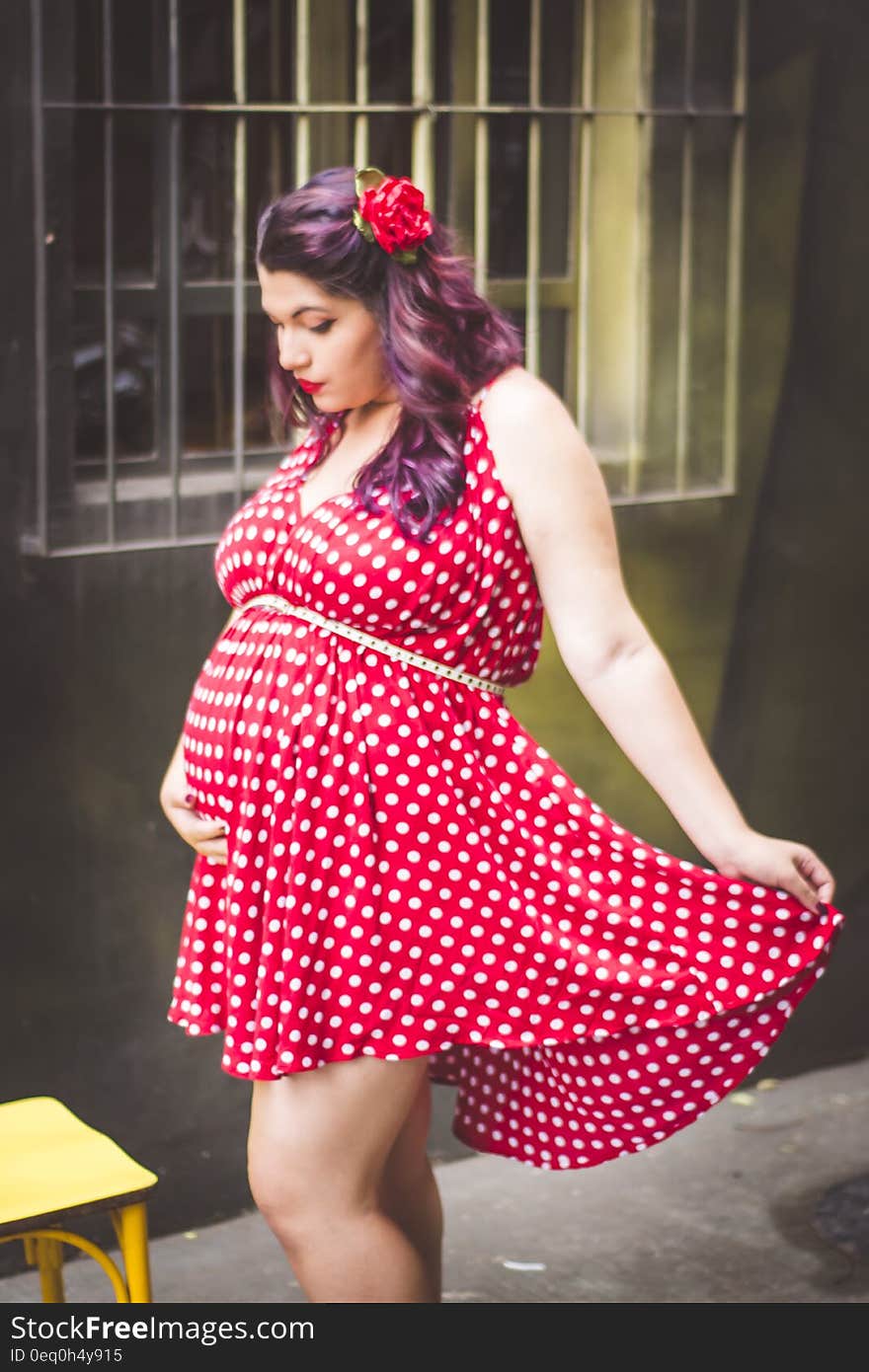 Woman in Red and White Polka Dots Mini Dress Holding Her Stomach