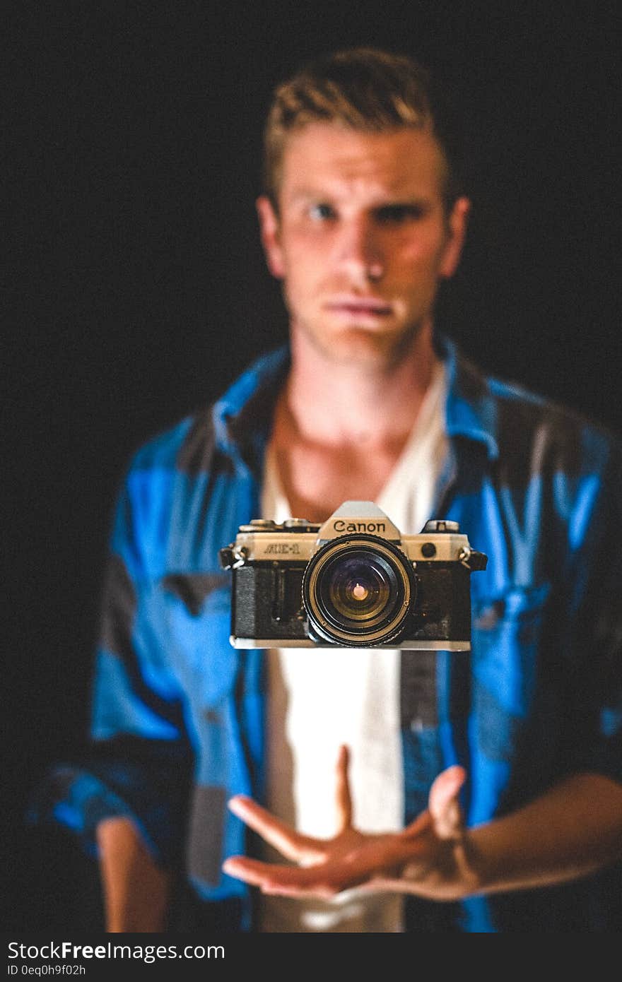 Portrait of man in blue shirt appearing to levitate Canon camera. Portrait of man in blue shirt appearing to levitate Canon camera.