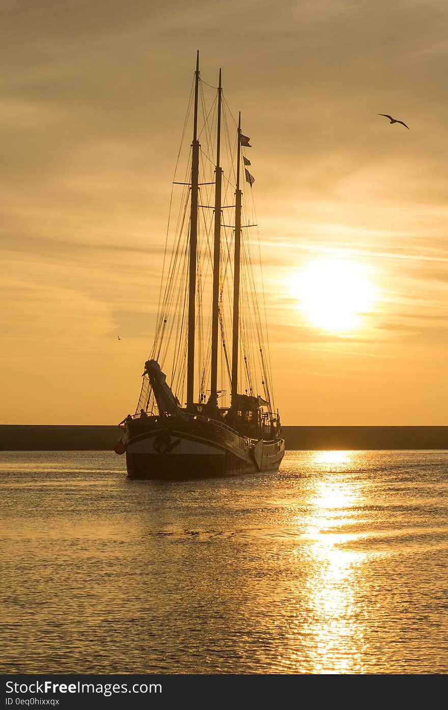 Sailboat off coastline at sunset. Sailboat off coastline at sunset.