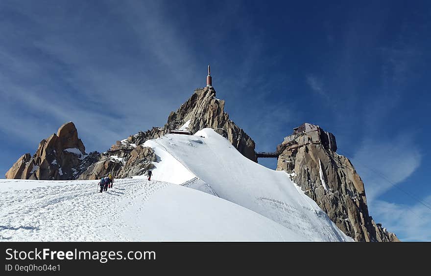 People Walking Toward Top of Mountain on Snow Covered Ground during Daytime