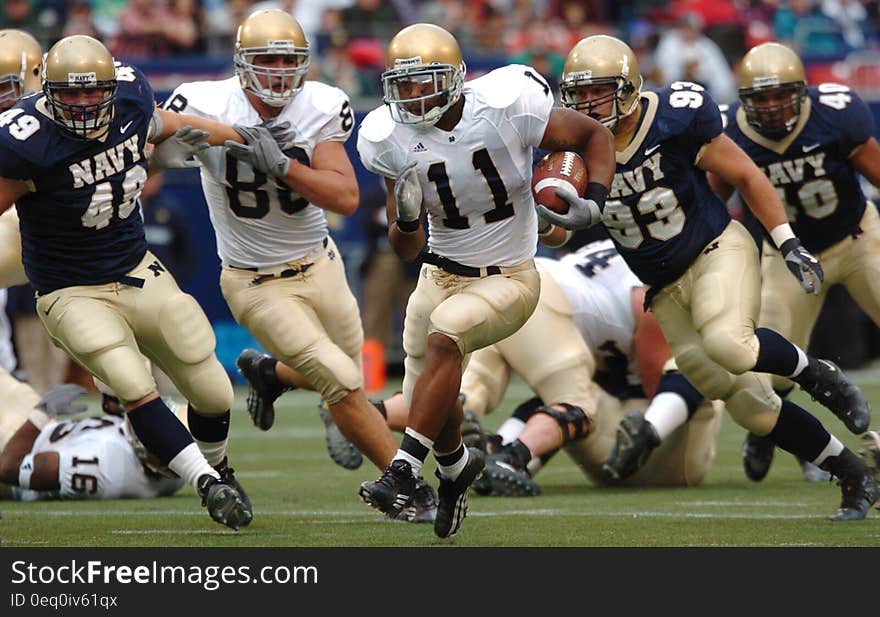 Group of Male Football Players Running on Field during Day